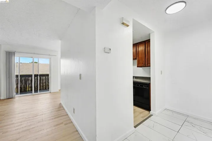 Bright interior featuring light wood-finish flooring, white walls, and a sliding glass door opening to an exterior balcony