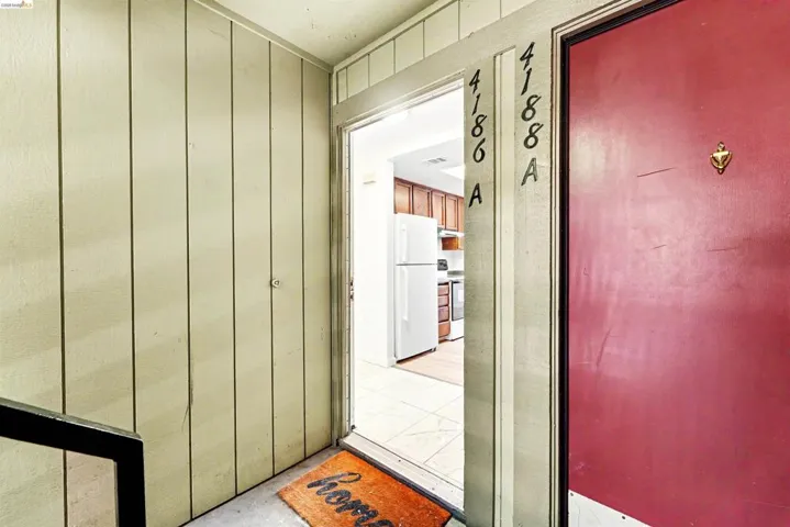 Entryway featuring paneled wall finishes and a contrasting red door with a brass knocker