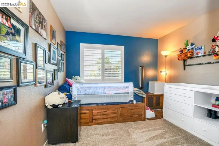 Bedroom with light colored carpet and a textured wall