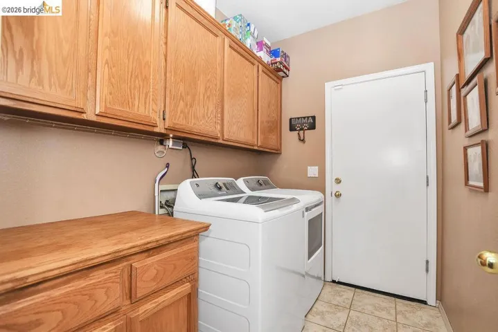 Laundry area with cabinet space, washing machine and clothes dryer, and light tile patterned flooring