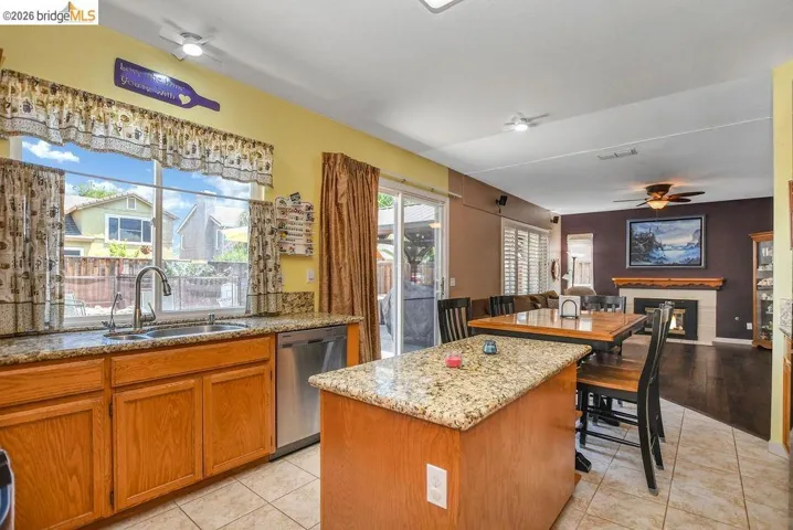 Kitchen with a kitchen island, a glass covered fireplace, a ceiling fan, and light tile patterned floors