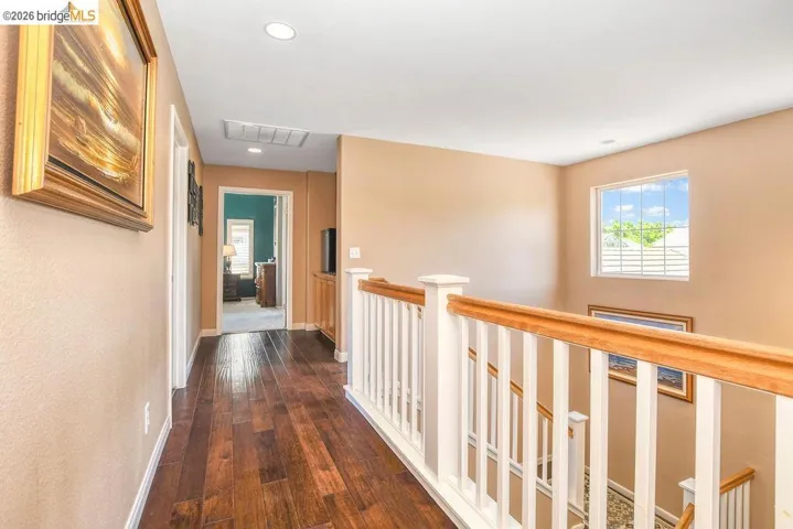 Corridor with dark wood-type flooring, an upstairs landing, and recessed lighting