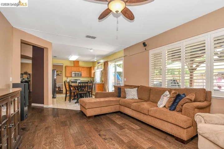 Living area with a ceiling fan and dark wood-type flooring