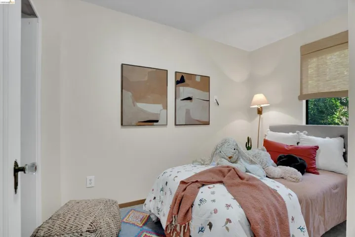 White walls with two framed art pieces, a window with a woven shade, and a door with a glass knob