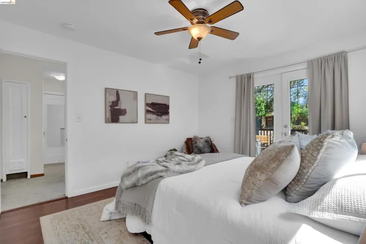 Bedroom featuring hardwood flooring, white walls, and a ceiling fan with integrated lighting