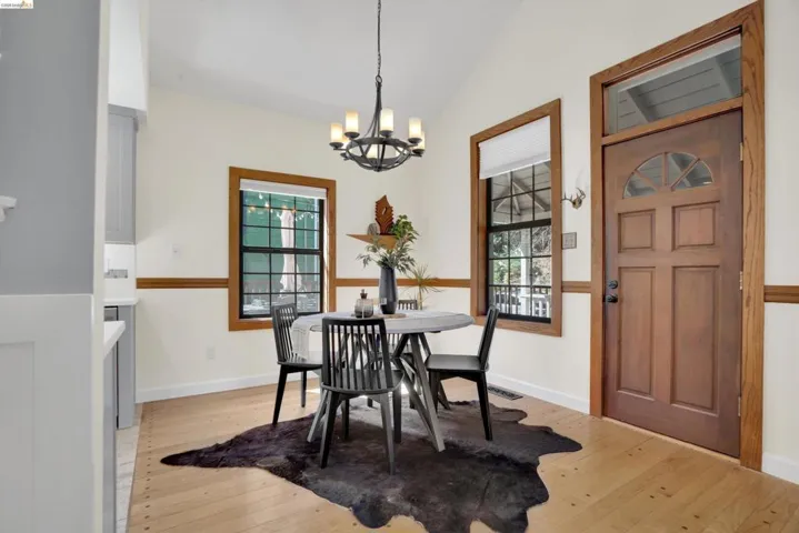 Dining area featuring light wood-finish flooring, a vaulted ceiling, and a dark bronze chandelier