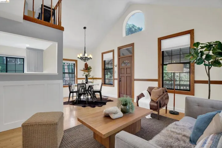 Vaulted ceilings with an arched window, wood-finish flooring, and natural wood trim throughout
