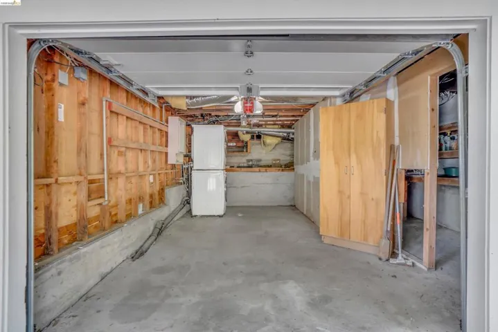 Spacious garage featuring a concrete floor, exposed wooden wall framing, and built-in wood-finish cabinetry