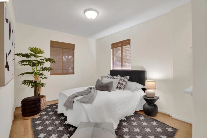 Bright room featuring two windows with woven wood blinds, light-toned walls, wood-finish flooring, and a flush-mount ceiling light fixture