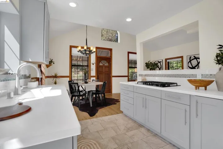 Kitchen featuring light gray cabinetry, white countertops, stainless steel sink with a gooseneck faucet, a tiled backsplash, and recessed lighting