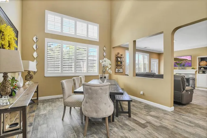 Dining area featuring high ceilings, wood-finish flooring, and multiple windows with plantation shutters