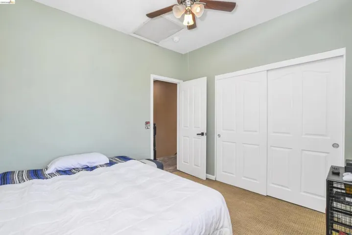 Bedroom featuring light green walls, a ceiling fan with integrated lighting, and carpet flooring