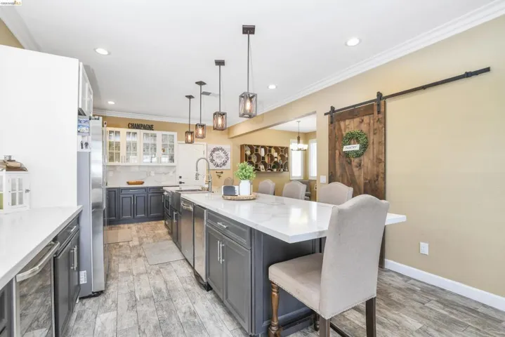 Kitchen featuring a large central island with seating, white countertops, and pendant lighting