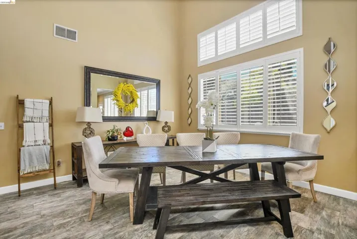 Dining area featuring high ceilings, wood-finish flooring, and multiple windows with white plantation shutters