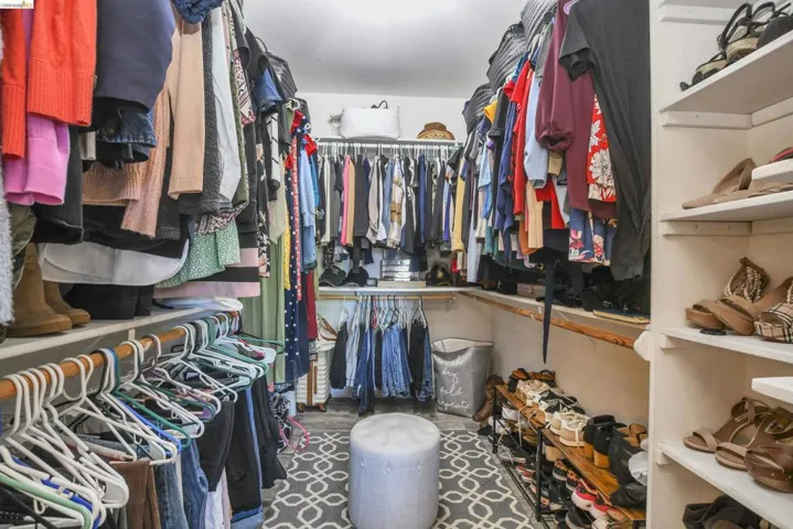 Walk-in closet featuring extensive built-in shelving, multiple hanging rods, and a patterned area rug