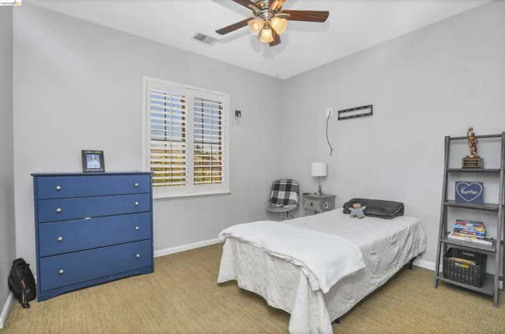 Carpeted room with a ceiling fan featuring integrated lighting