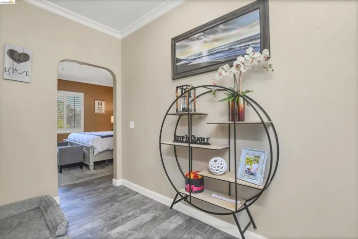 Archway entry featuring crown molding and wood-finish flooring