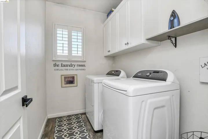 Dedicated laundry space featuring a window with white louvered shutters