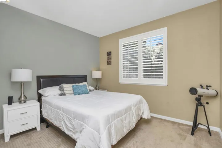 Carpeted room featuring a window with white plantation shutters, two-tone painted walls, and white baseboards