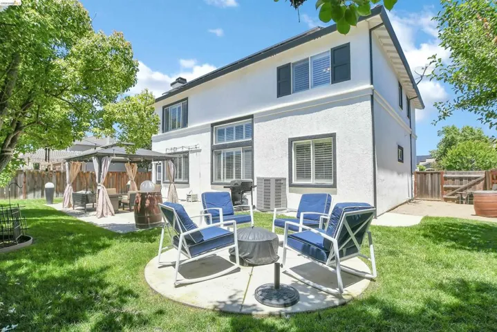 Expansive backyard featuring a manicured lawn, a paved patio with a gazebo, and a circular concrete pad