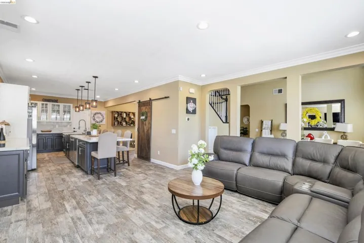 Open-concept living area featuring wood-finish flooring, recessed lighting, and crown molding