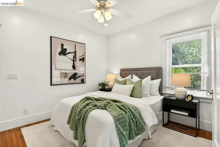 Bright room featuring hardwood flooring, a white ceiling fan with integrated lighting, a single window with blinds, and white baseboards