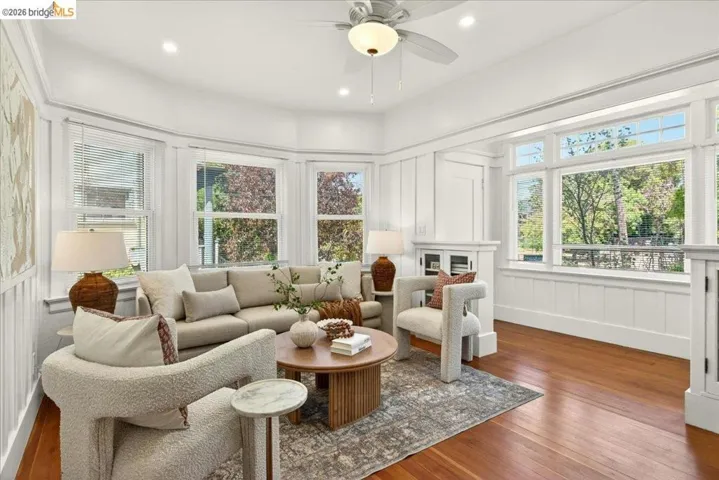 Living area featuring abundant natural light from multiple windows, rich wood-finish flooring, recessed lighting, a ceiling fan, and built-in cabinetry with glass fronts
