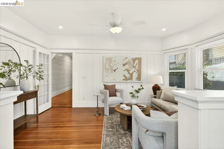 Living area featuring rich wood flooring, crisp white board and batten wall paneling, recessed lighting, and a ceiling fan