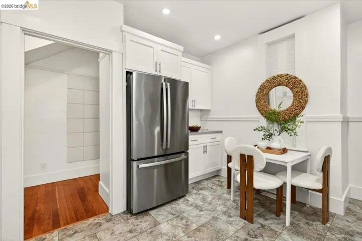 Modern kitchen featuring a stainless steel refrigerator, white cabinetry, light countertops, and recessed lighting
