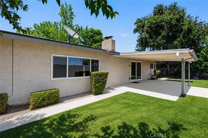 Private backyard with lawn area, mature trees, and covered patio access.