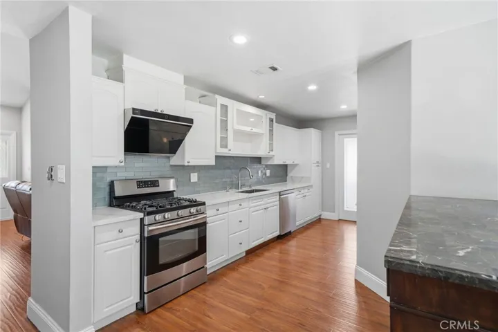 The remodeled kitchen features slab quartz countertops, upgraded cabinetry with pantry drawers, stainless steel appliances, recessed lighting, and abundant storage.