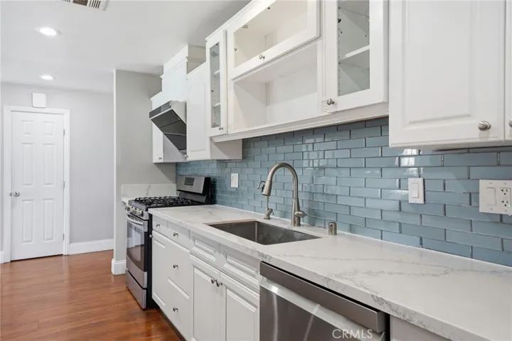 The remodeled kitchen features slab quartz countertops, upgraded cabinetry with pantry drawers, stainless steel appliances, recessed lighting, and abundant storage.