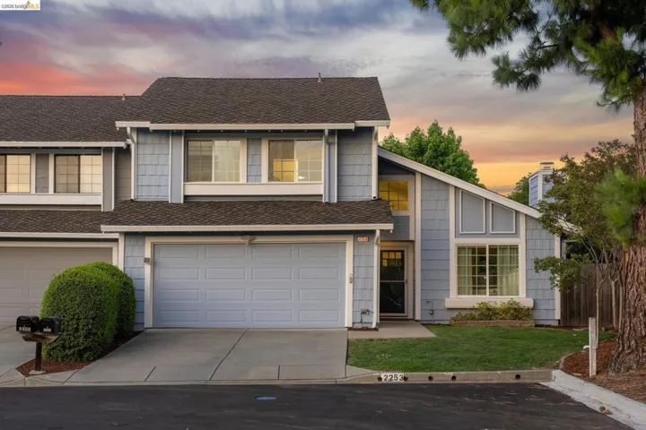 Light blue siding exterior featuring multiple window styles, an attached garage, and a covered entry