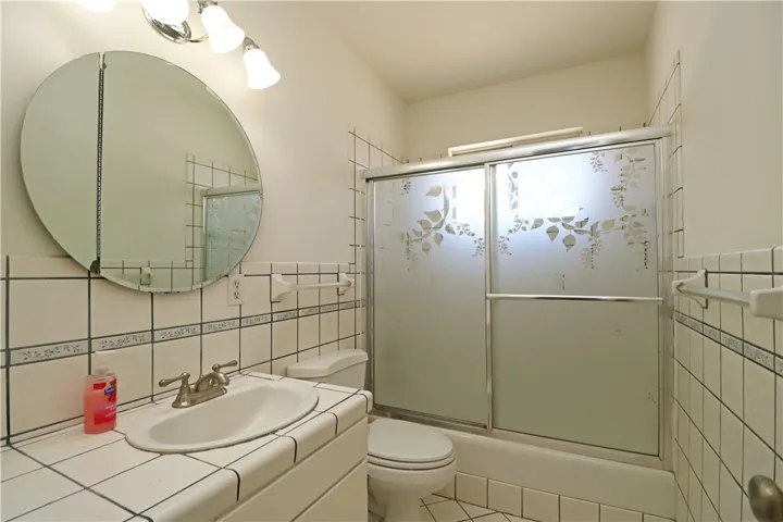 Hall bathroom with tile counters and wainscot.