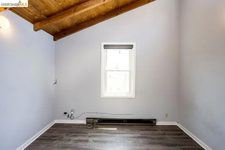 Vaulted wood-plank ceiling with exposed beams, light gray walls, and wood-finish flooring
