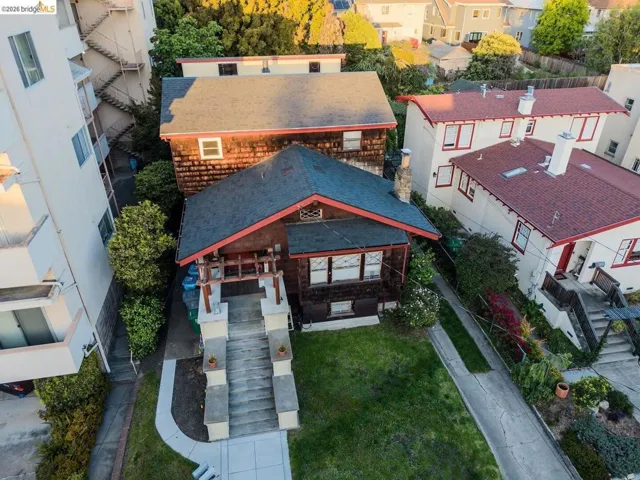 Craftsman-style residence featuring a prominent gabled roof with dark shingles, natural wood siding, and contrasting red trim