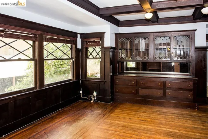 Hardwood flooring, dark wood wainscoting, and a built-in buffet with leaded glass cabinetry