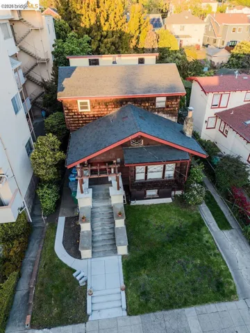 Craftsman-style residence featuring a dark shingle exterior, red trim accents, and a covered front porch with substantial pillars
