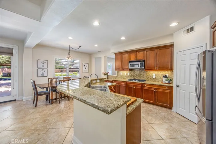 Spacious kitchen featuring granite countertops, generous cabinetry, and a large peninsula with bar seating