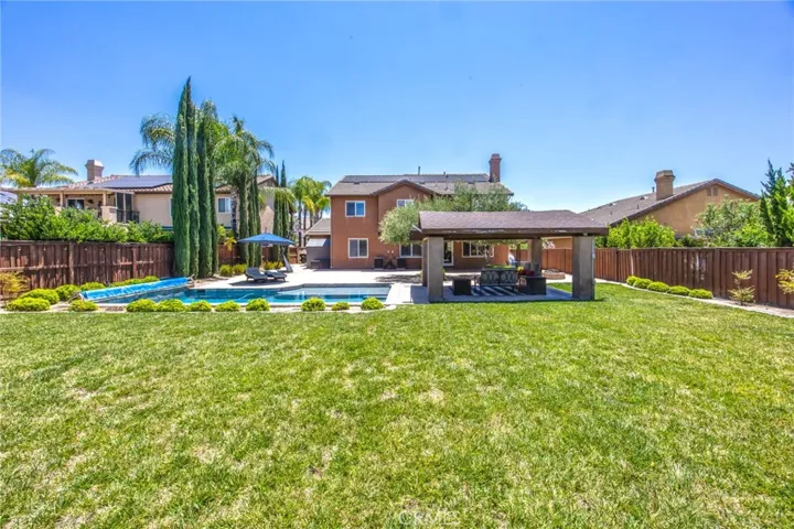 Expansive backyard featuring a pool, spa, covered pavilion, and generous lawn area