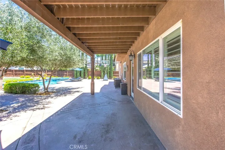 Covered patio offering a shaded space for outdoor entertaining beside the pool