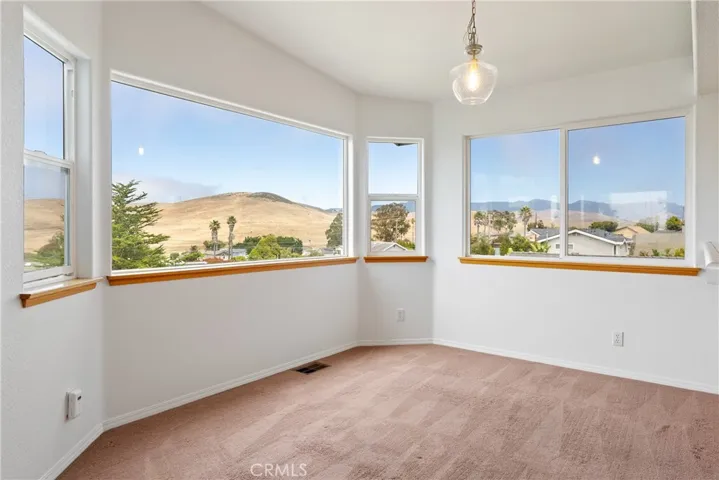 Sunlit dining area surrounded by expansive windows that frame hillside and neighborhood views.