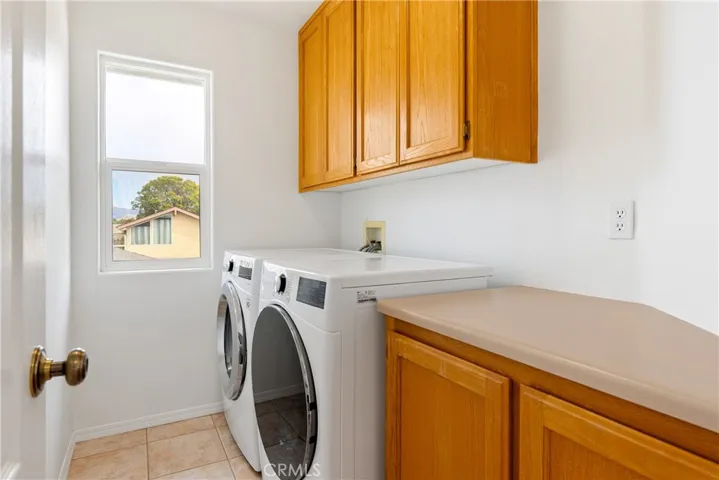 Dedicated laundry room with overhead cabinetry, countertop workspace, and natural light from the adjacent window.  Washer and dryer Included