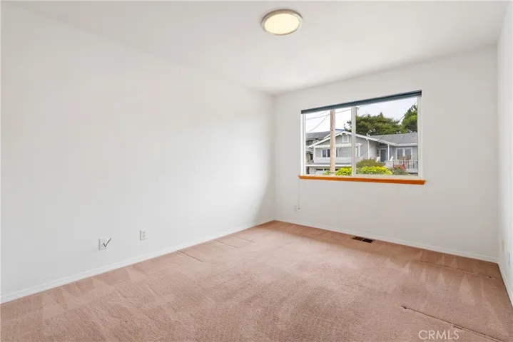 Bright secondary bedroom with a large window, neutral finishes, and flexible use as a guest room, office, or hobby space.