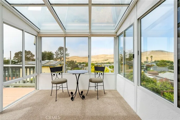 Bright enclosed sunroom with floor-to-ceiling windows, offering a comfortable space to relax while enjoying panoramic views.