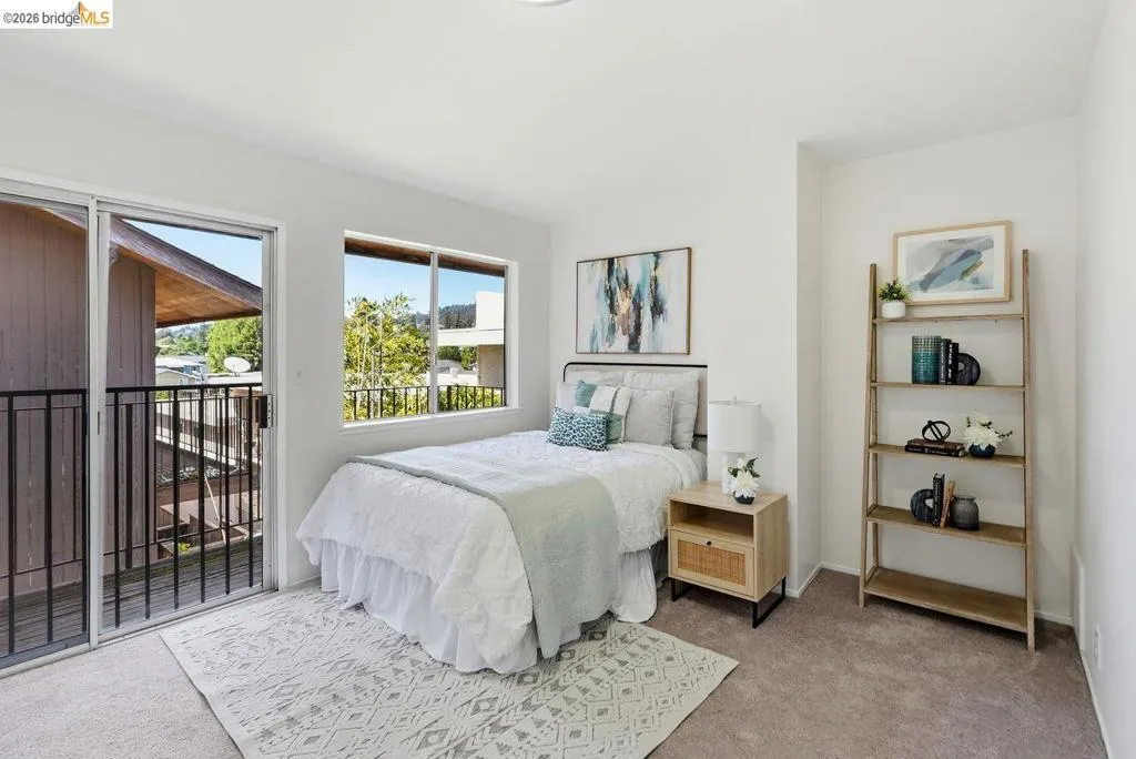 Carpeted room featuring a sliding glass door to a private balcony, a large window, and a built-in shelving unit