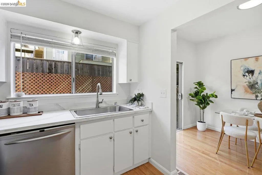 Kitchen area featuring a stainless steel sink, white cabinetry, and light countertops with a matching backsplash