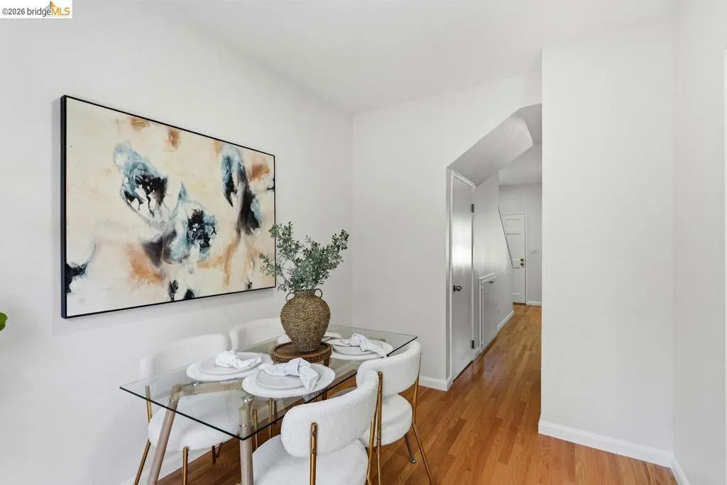 Dining area featuring wood-finish flooring, white walls, and an arched doorway