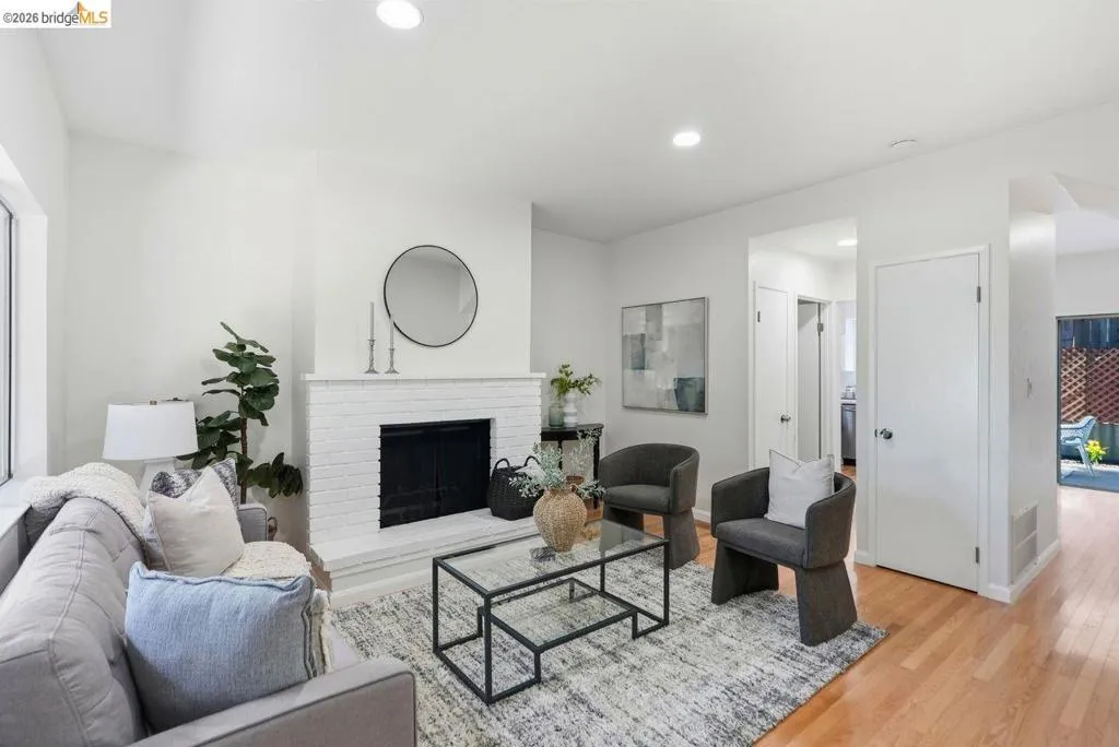 Bright living area with a white brick fireplace, recessed lighting, and wood-finish flooring