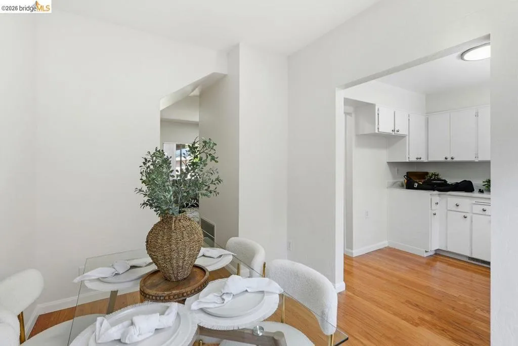 Dining area featuring a glass-top table, white walls, and wood-finish flooring